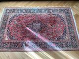 a close up of a rug on a wooden floor with a couch in the background