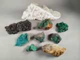 several different colored rocks and minerals on a white surface