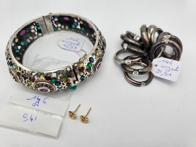 un gros plan d'un bracelet et d'une boucle d'oreille posés sur une surface blanche