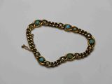 un gros plan sur un bracelet en or orné de pierres de turquoise
