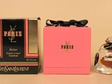 un flacon de parfum et un coffret de parfum posés sur une table, à côté d'une boîte rose