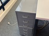a desk with a filing cabinet in the corner