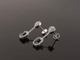 a pair of diamond earrings on a black surface