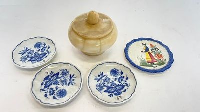 quatre petites assiettes bleues et blanches et un petit bol posés sur une table