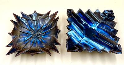two pieces of blue glass sitting on a white surface