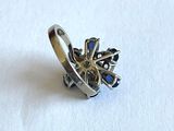 une bague en argent ornée de pierres bleues sur un fond blanc