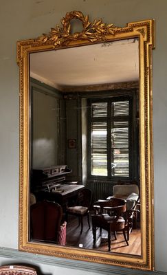 un miroir accroché au mur dans lequel se reflète une pièce où se trouve un piano