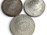 three silver coins sitting on top of each other on a white surface