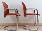 pair of red leather chairs with chrome legs in a white room