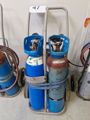 Plusieurs bouteilles de gaz propane sont empilées sur un chariot dans un garage