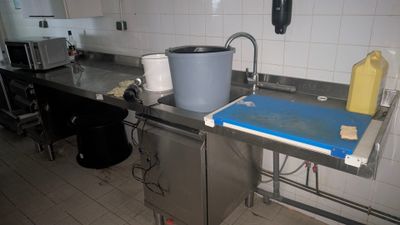 une cuisine équipée d'un évier et d'une poubelle posée sur le plan de travail