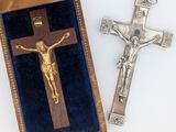 une croix en argent et un crucifix en bois dans un écrin