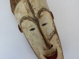 un vieux masque en bois accroché à un mur sur fond blanc