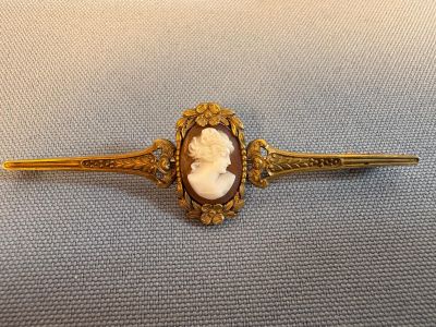 un gros plan sur une broche dorée et blanche représentant un chat