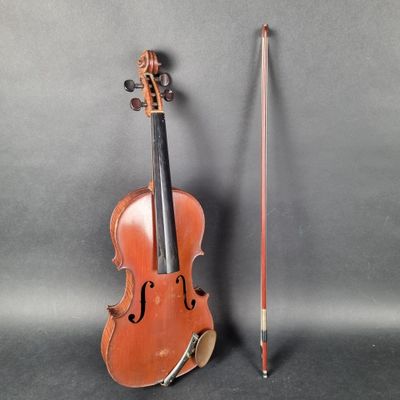 an old violin sitting next to a violin stick on a gray surface