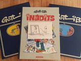 Trois livres sont posés sur une table en bois ; l'un d'entre eux comporte le dessin d'un homme et l'autre, celui d'un chat