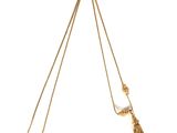 a close up of a gold necklace with a tassel on a white background