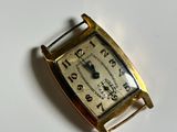 a small gold wrist watch on a white surface
