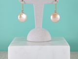 une paire de boucles d'oreilles en perles posée sur un présentoir, sur fond turquoise