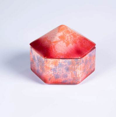 une boîte rouge et rose avec un couvercle, posée sur une surface blanche