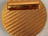 a close up of a gold tie bar on a white cloth