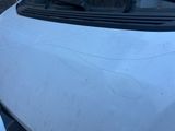 une voiture blanche dont le capot est fissuré et le pare-brise cassé