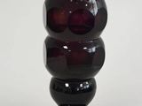un vase noir et rouge posé sur une surface blanche
