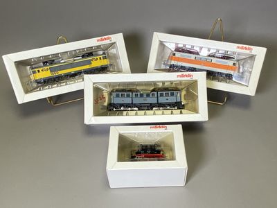 trois trains miniatures sont exposés dans une vitrine posée sur une table
