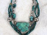 un gros plan d'un collier orné d'une pierre turquoise et de perles en argent