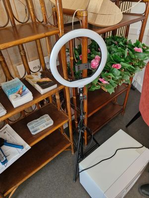 une femme debout devant une caméra, avec une lampe annulaire