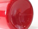 un gobelet rouge posé sur une surface blanche, sur fond blanc