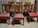 six chaises en bois avec des assises rembourrées rouges dans une pièce