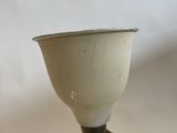 a small white vase sitting on top of a table