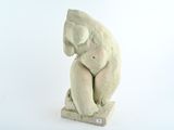 une petite statue représentant un ours assis sur un bloc