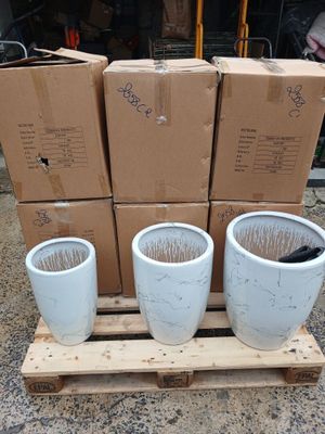 three white planters sitting on a pallet with boxes in the background