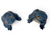 two blue frogs that are sitting on a white surface