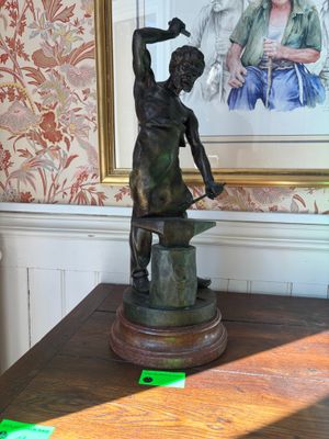 a bronze statue of a woman holding a hammer on a table