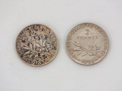 two coins that are sitting side by side on a white surface