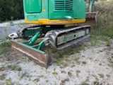 a green and yellow excavator that is sitting in the dirt