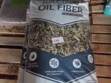 un sac de fibres d'huile posé sur une palette à côté d'un tas de bois
