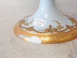 a blue and gold vase on a table with a tag on it