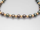 a black pearl and gold beaded necklace on a white surface