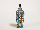 un vase bleu et blanc avec un couvercle noir posé sur une surface blanche