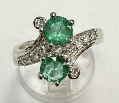a close up of a ring with two emerald stones on it