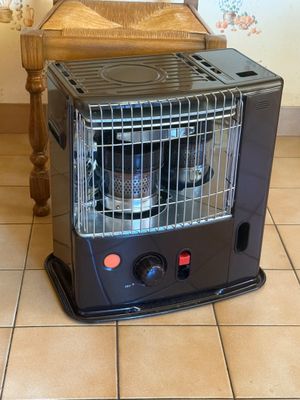 a black heater sitting on a tiled floor next to a chair