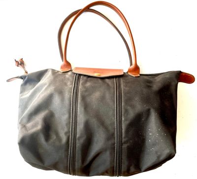 black leather handbag with brown leather handles on a white background