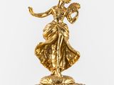 a gold clock with a woman on top of it