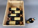 bottles of wine in a wooden box next to a bottle of wine