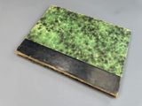 an old book with a green and black cover sitting on top of a table