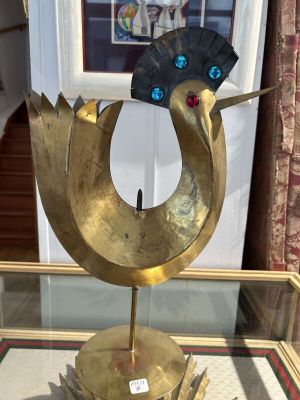 brass sculpture of a bird with a fan on top of a glass table